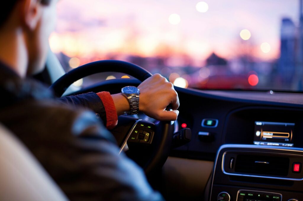 Driver with his hand on the steering wheel at dusk