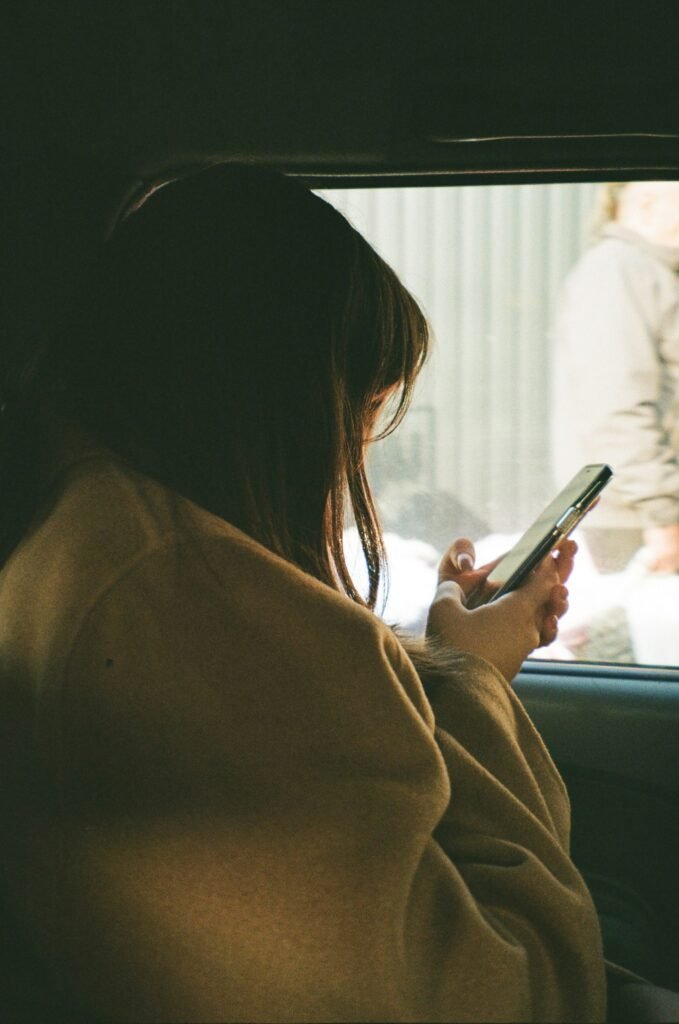 Passenger checking her phone in the back of a car